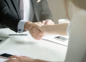 Closeup of male and female hands handshaking after effective negotiation showing mutual respect and intention for strong working relationships. Man in suit greeting female partner. Business concept